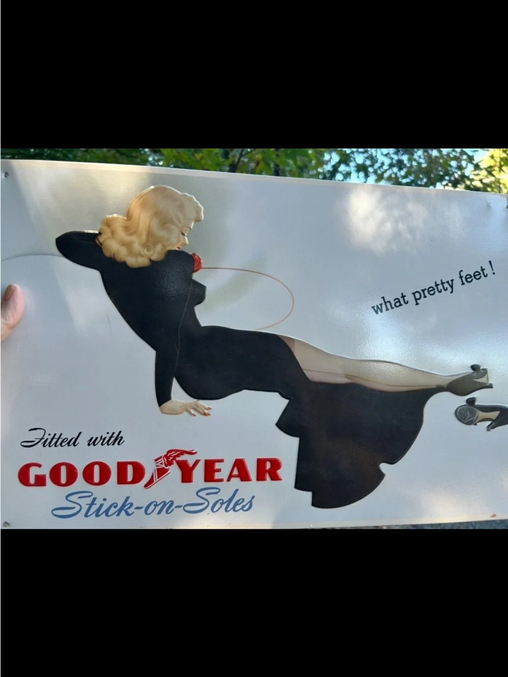 Vintage-style metal sign features a retro advertisement for Goodyear